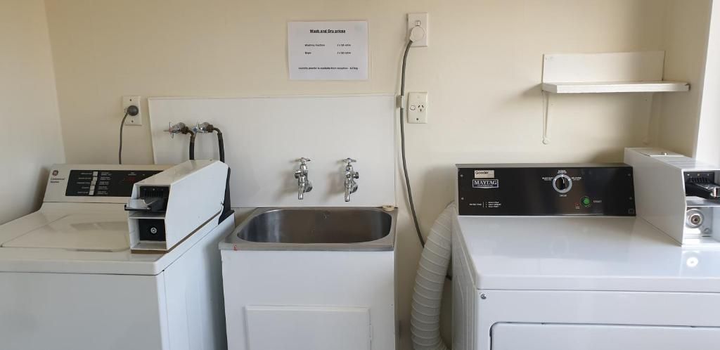 A laundry area with three washing machines, a sink, and a wall-mounted heater.
