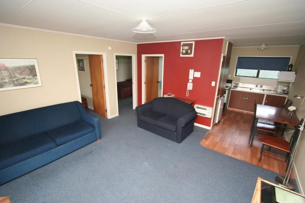 Un espacio habitable compacto con sofá, un pequeño sofá, kitchenette y comedor.