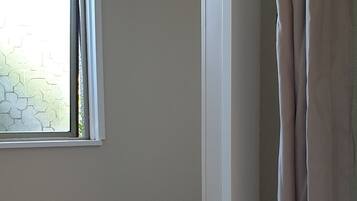A bathroom with a window, a shower curtain, and a toilet.