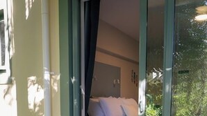 A room with a bed, a glass door leading to a balcony, and a table with chairs. - La Rochelle Motel (Akaroa)