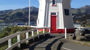 Un faro con puerta roja, paredes blancas y un balcón.