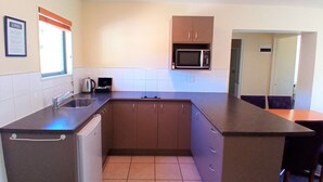 A compact kitchen with a built-in microwave, a sink, and a compact refrigerator. - La Rochelle Motel (Akaroa)