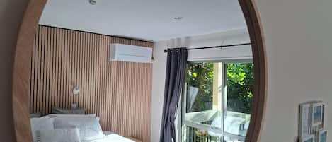 A bedroom with a bed, a window, and a wall-mounted air conditioning unit.