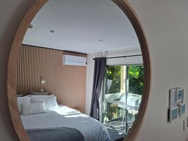 A bedroom with a bed, a window, and a wall-mounted air conditioning unit.