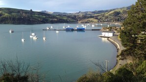 A coastal marina with boats docked, a pier, and a small white building with a red roof. - La Rochelle Motel (Akaroa)