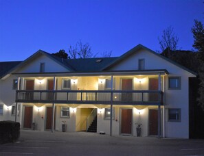 A two-story building with a balcony, multiple doors, and a staircase leading to the upper level.