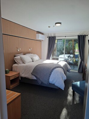 A modern bedroom with a bed, bedside tables, a desk, and a view of the outdoors. - La Rochelle Motel (Akaroa)