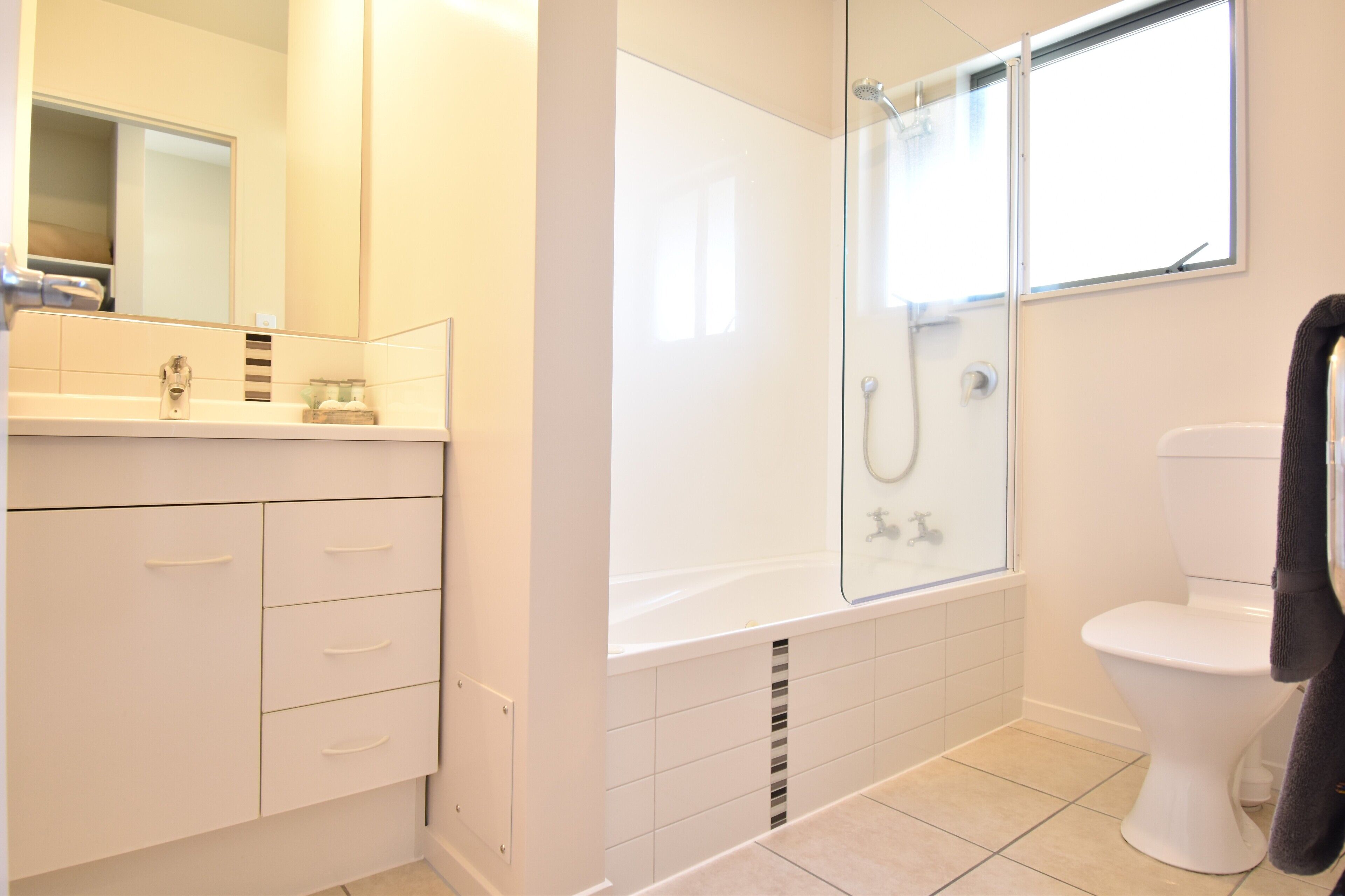 Un baño moderno con ducha acristalada, inodoro blanco y tocador con cajones.