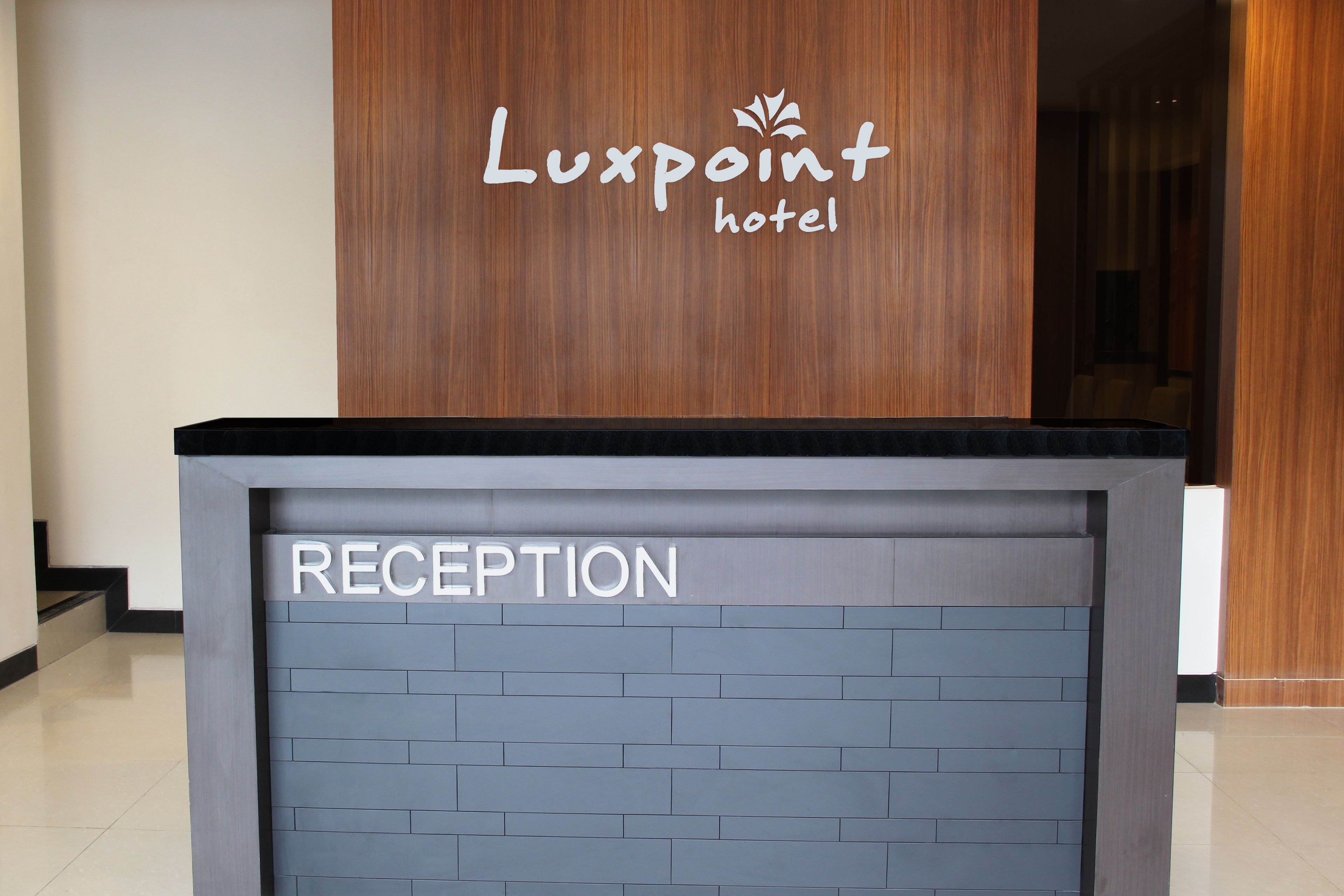 A reception desk at Luxpoint hotel with a sign indicating the reception area.