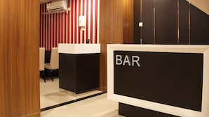 Uma área de recepção com um letreiro 'BAR', painéis de madeira e uma parede listrada de vermelho.