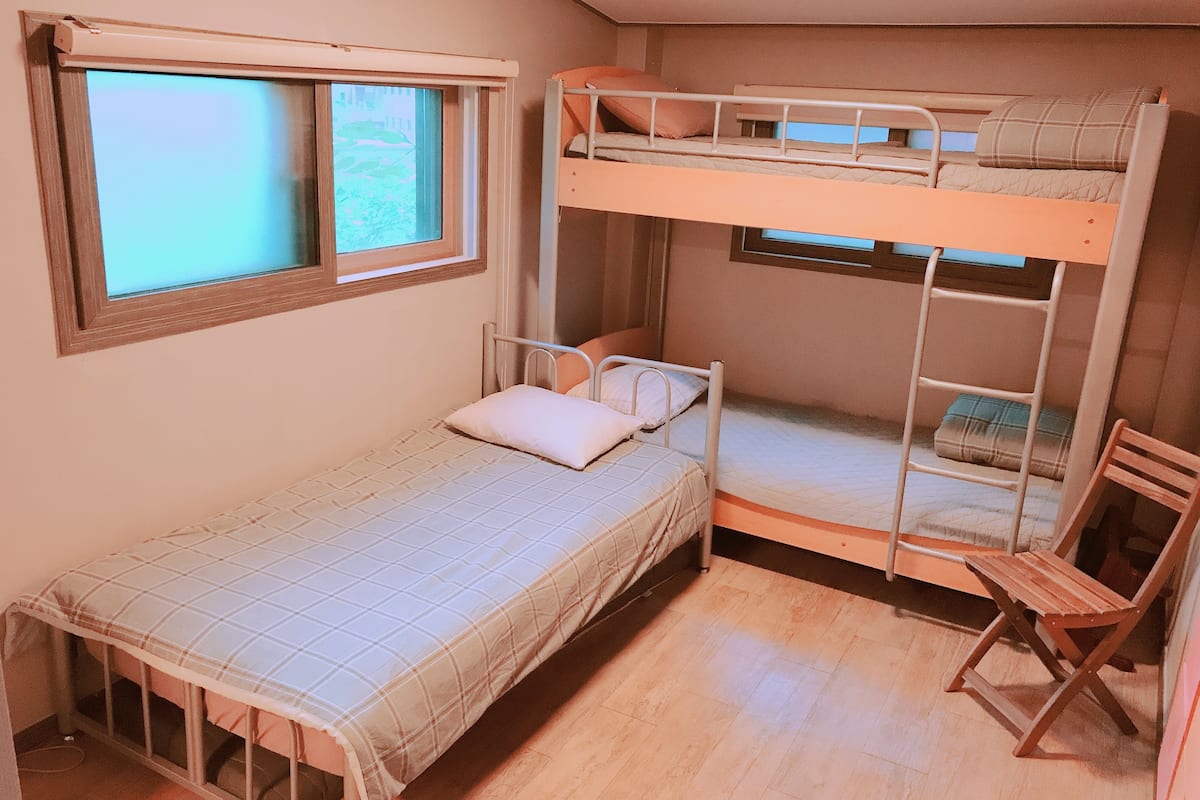 A bunk bed room with a single bed and a window.