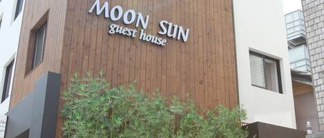 En moderne bygning med en træfacade og et skilt, der står 'MOON SUN guest house'.