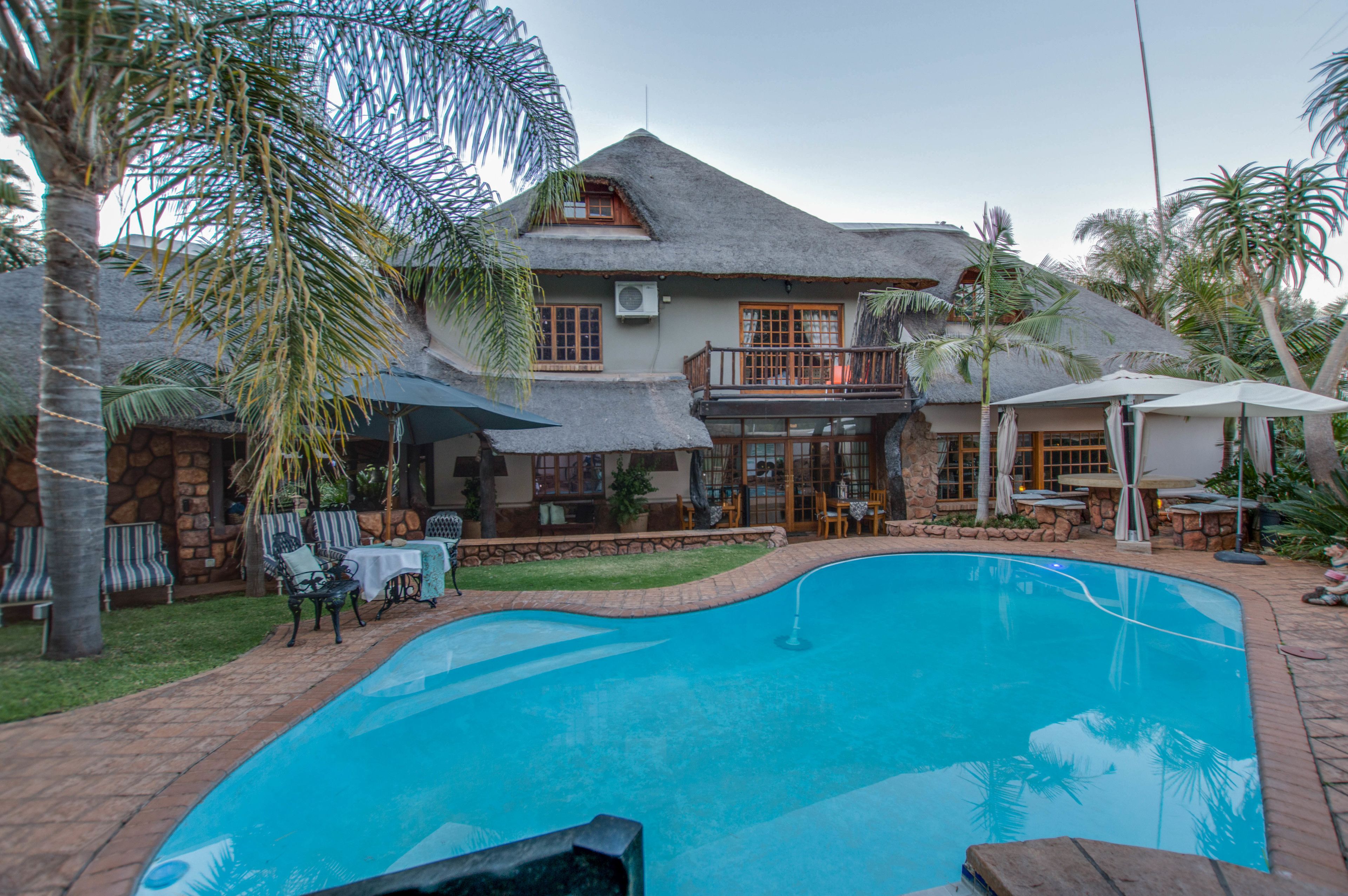 A house with a swimming pool, outdoor furniture, and a thatched roof.