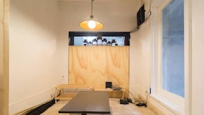 A room with a wooden wall, a table, a hanging light fixture, and a window.