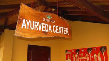 Ein hölzernes Schild mit der Aufschrift 'AYURVEDA CENTER', das über einer Tür hängt.
