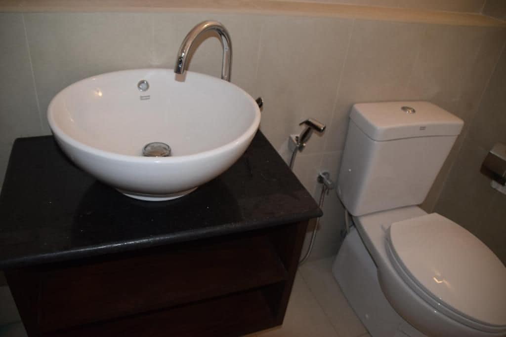 A bathroom with a white sink, a black countertop, and a white toilet.