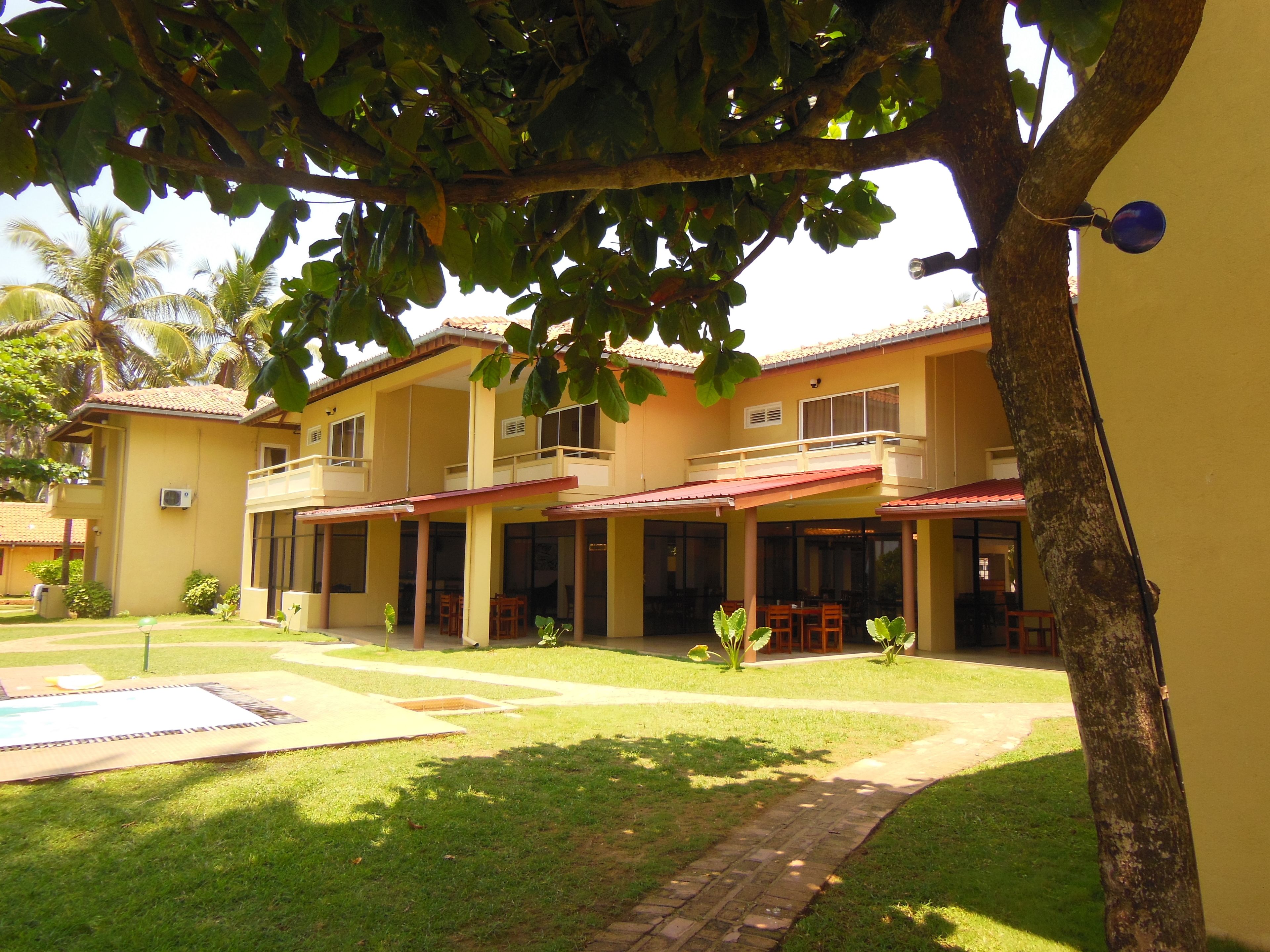 A two-story building with a balcony on the upper floor, a covered patio area, and a swimming pool.