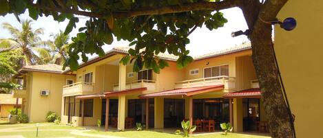 A two-story building with a balcony on the upper floor, a covered patio area, and a swimming pool.