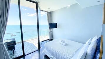 A hotel room with a bed, a TV, and a view of the sea.