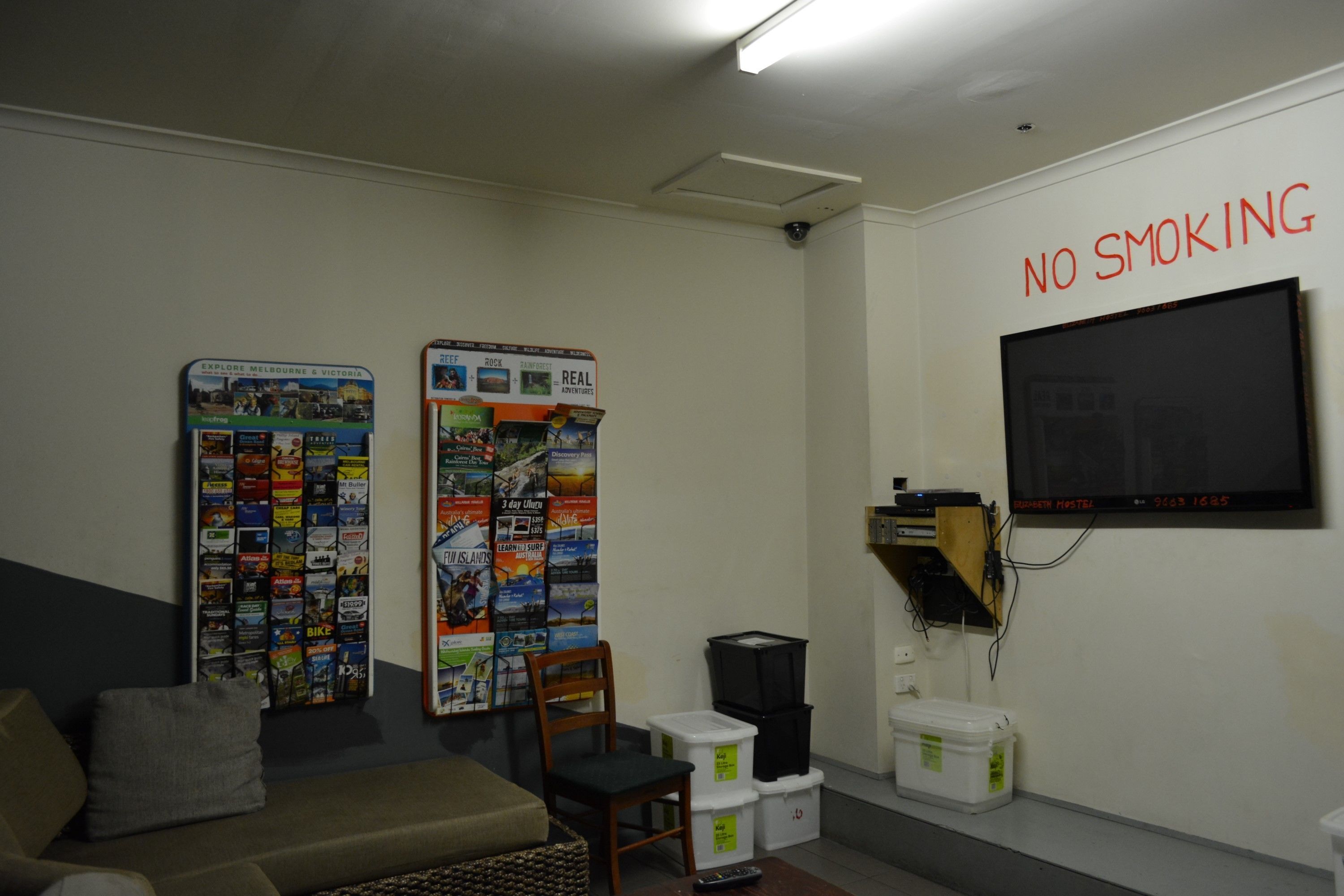 A room with a couch, posters on the wall, a TV, and storage bins.