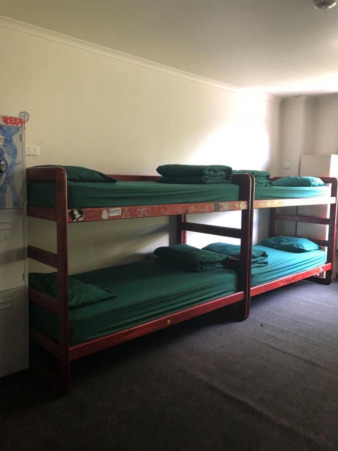 Une chambre avec un lit superposé, une literie verte et un sol recouvert de moquette.