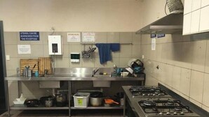 A kitchen with stainless steel appliances, a tiled floor, and various kitchen utensils and appliances on shelves.