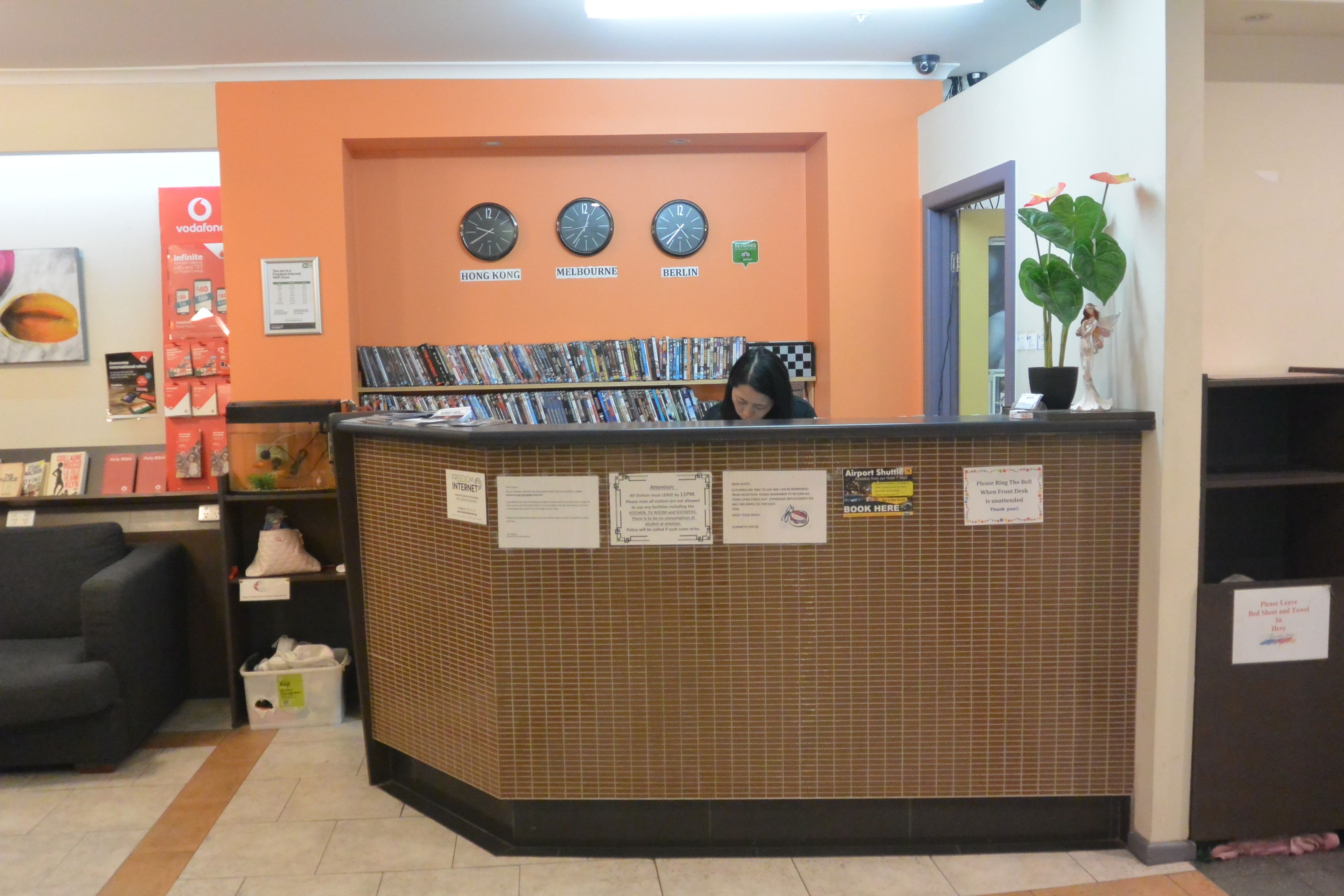 A reception area with a tiled counter, clocks displaying time in different cities, and a potted plant.