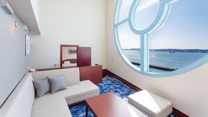 A modern room with a large window, a sofa, a small table, and a wooden cabinet.