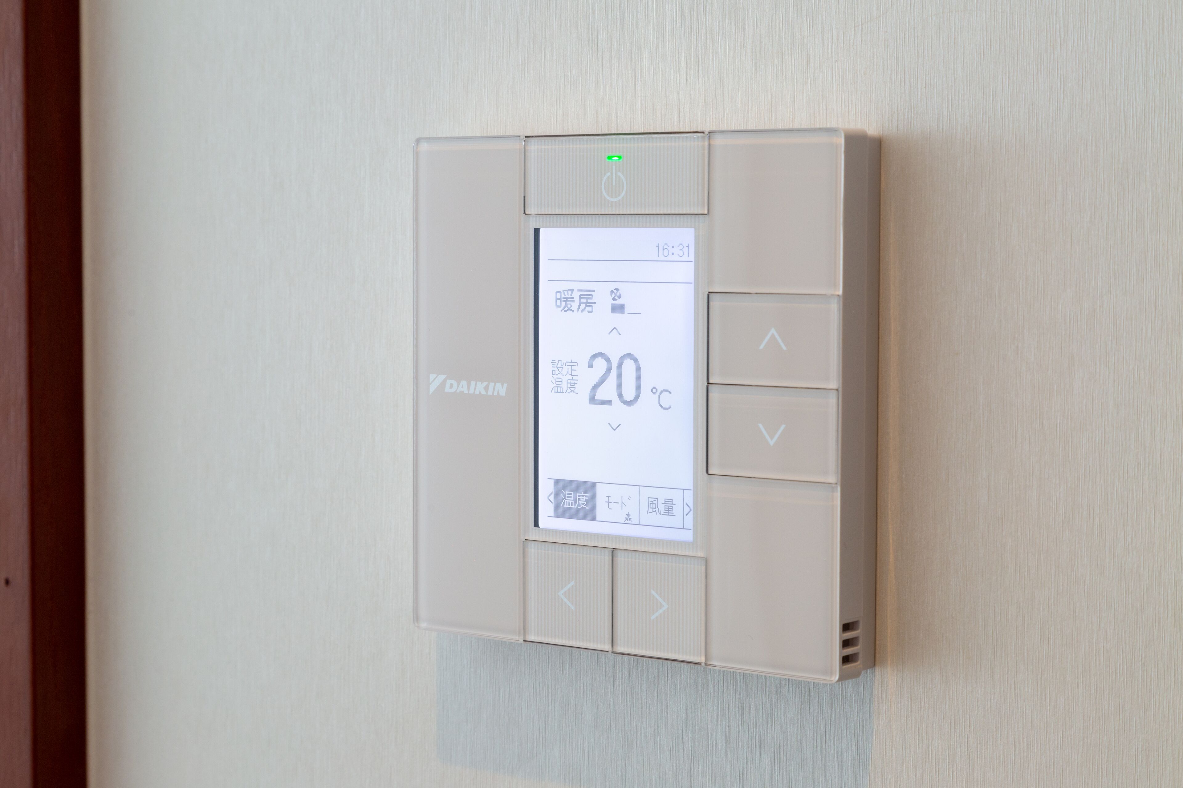 A thermostat mounted on a wall displaying a temperature of 20°C.