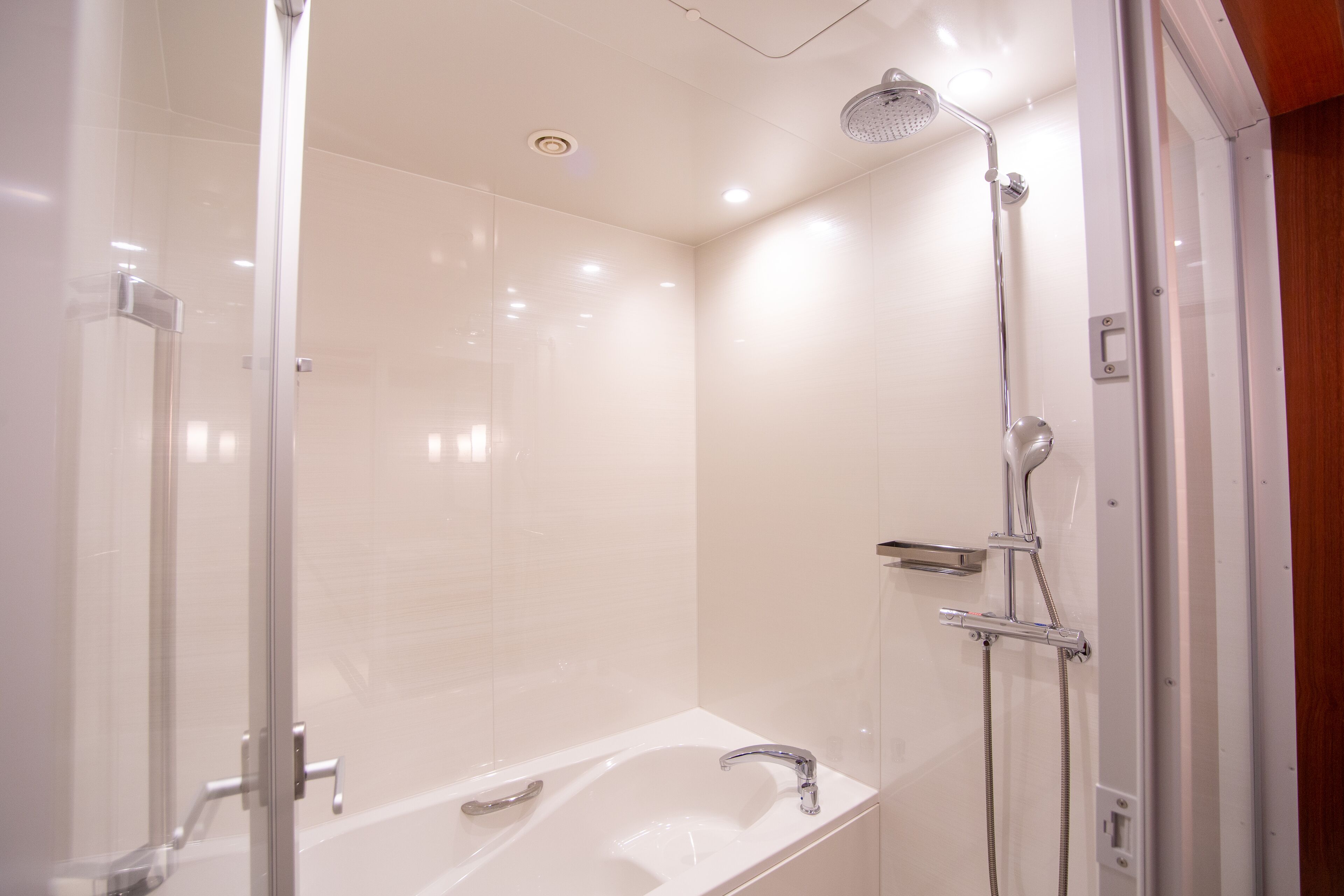 A modern bathroom with a glass-enclosed shower, a standalone bathtub, and a wall-mounted toilet.