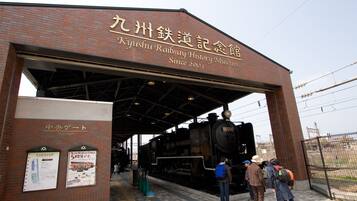 A railway museum entrance with a large brick building, a covered platform, and a steam locomotive.