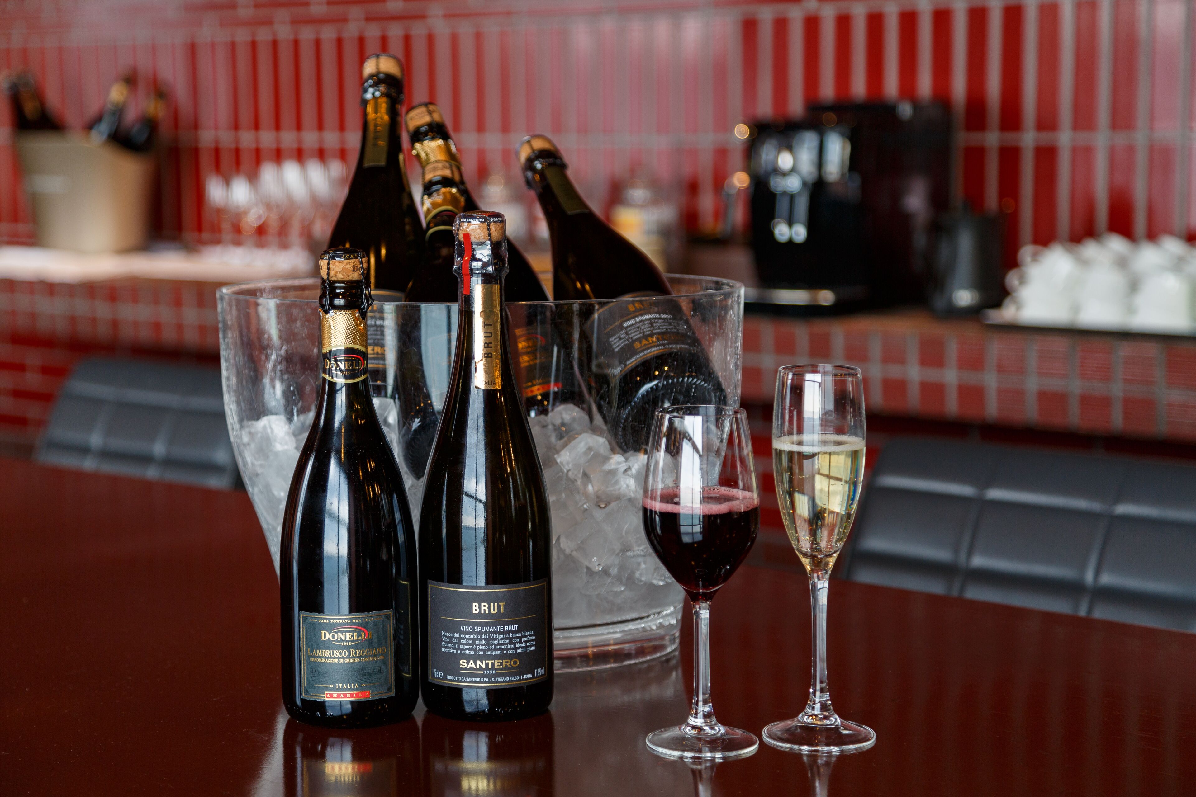 Un bar con botellas de Donella Brut y vino Santoro, hielo y copas.