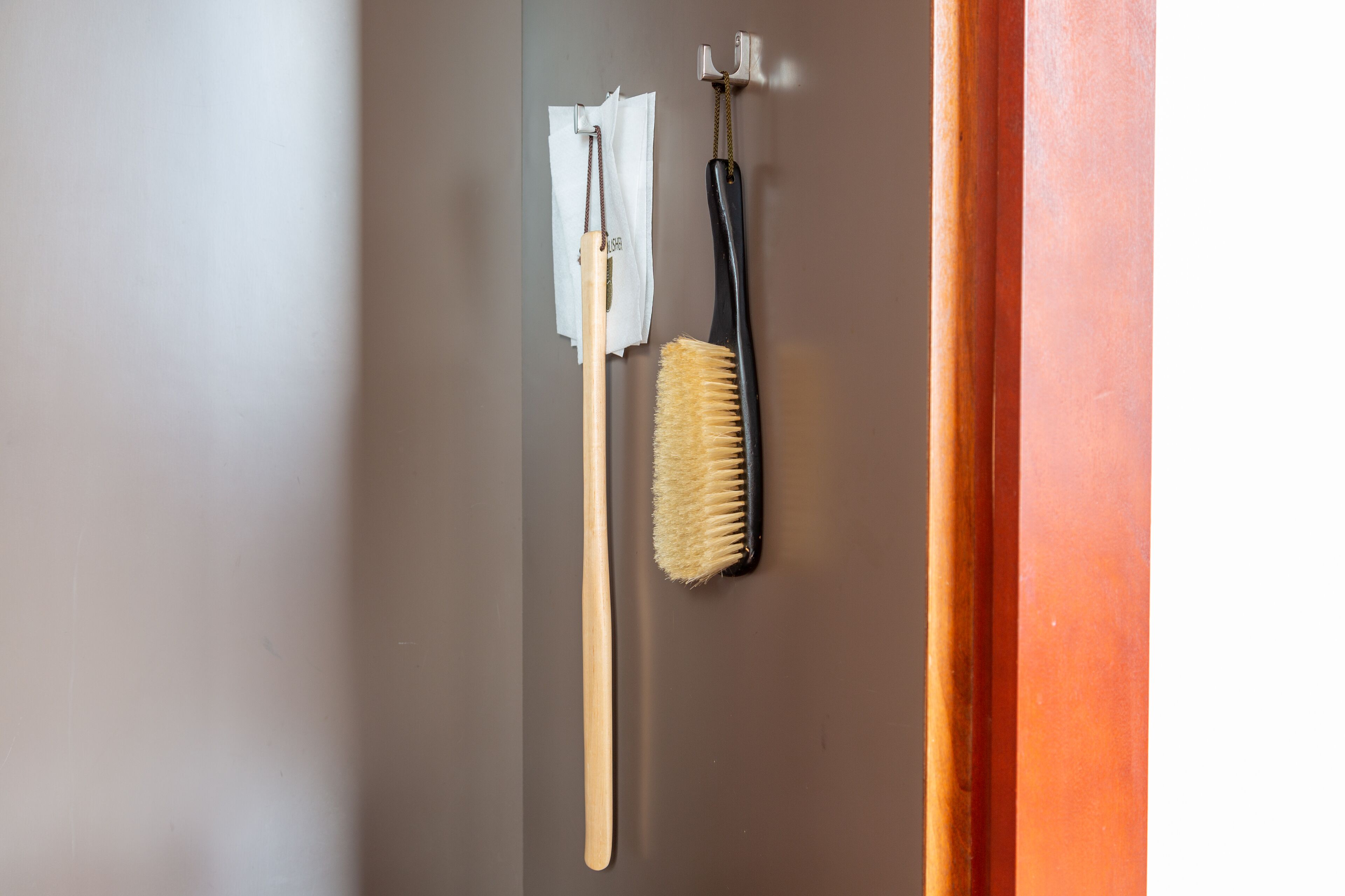 Un cepillo de madera y un cepillo con mango negro colgados en una pared.