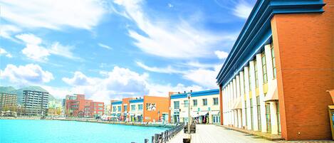 A waterfront promenade with buildings, a clear sky, and calm water.