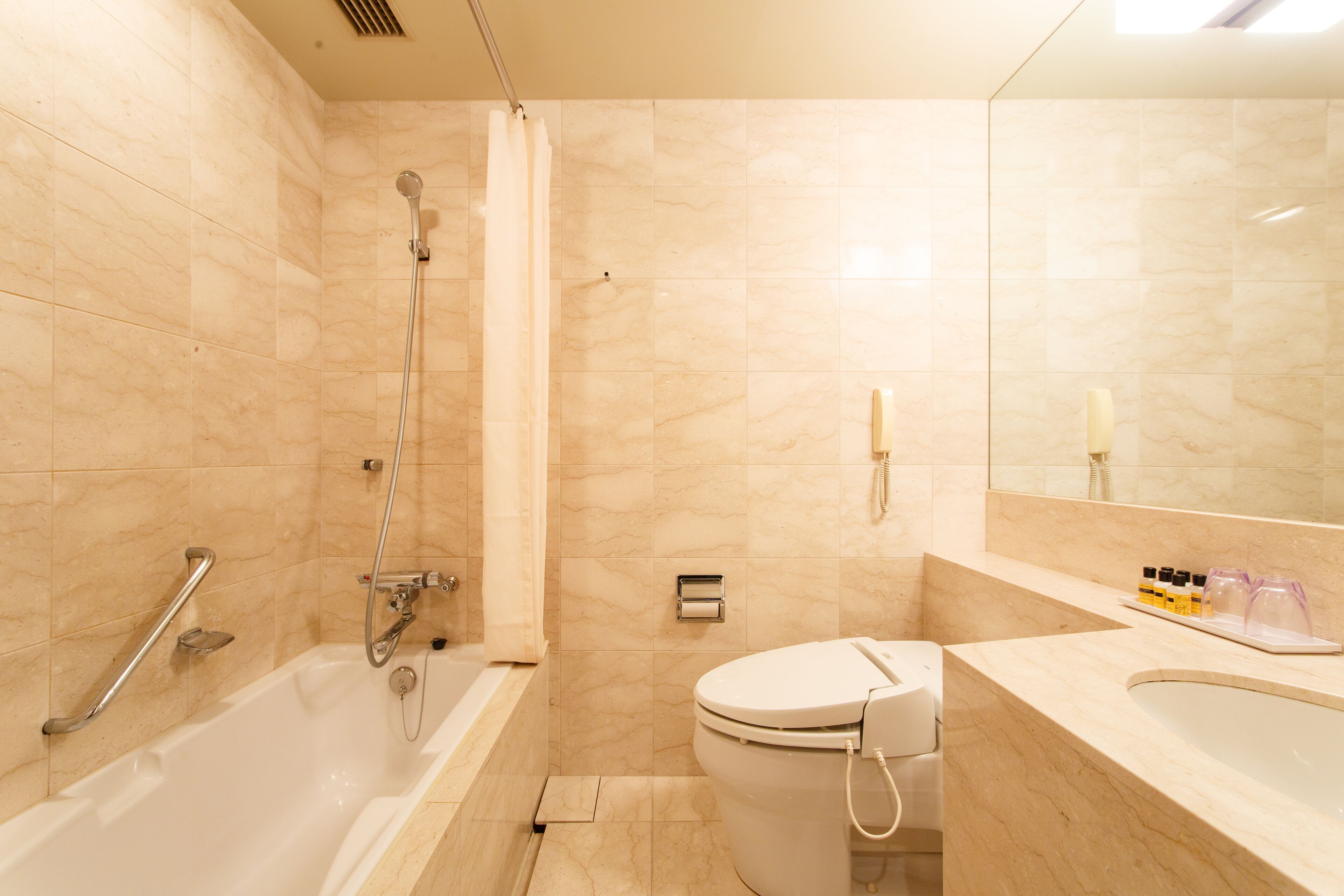 A modern bathroom with a bathtub, toilet, and shower.