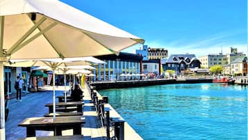A waterfront promenade with outdoor seating and a canal.