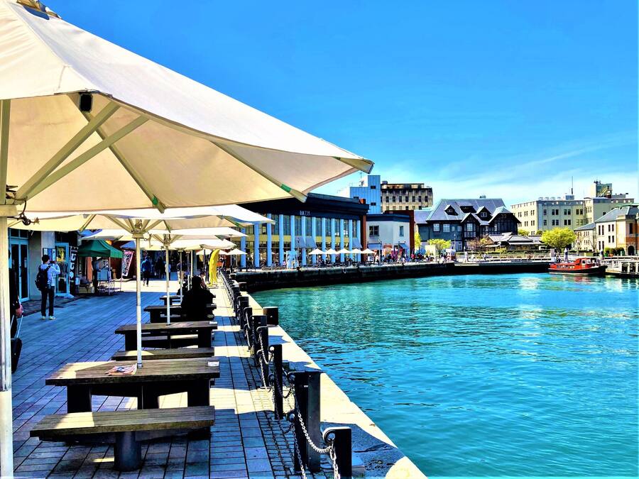 A waterfront promenade with outdoor seating and a canal.