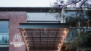 A boutique hotel entrance with a brick facade, a covered entrance area with string lights, and a visible reception desk. - Menlyn Boutique Hotel (Pretoria)