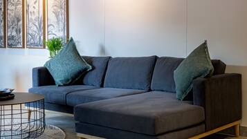 A modern living room with a sectional sofa, a coffee table, and artwork on the wall.