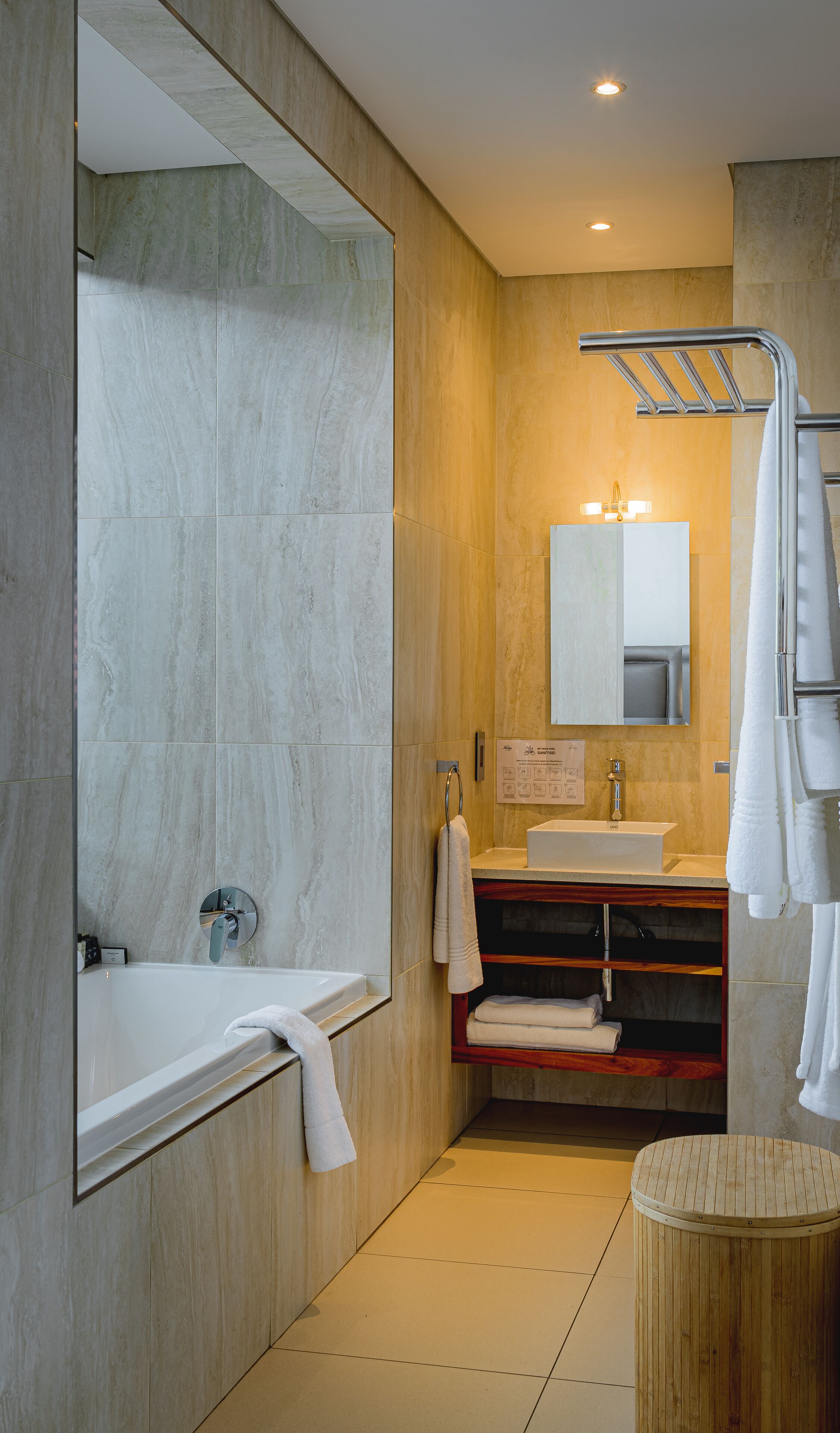 A modern bathroom with a bathtub, vanity, and a large mirror.