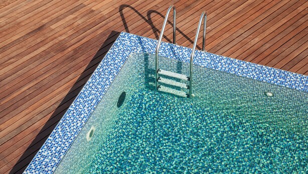 A swimming pool with a tiled edge and metal ladder, surrounded by a wooden deck. - Menlyn Boutique Hotel (Pretoria)