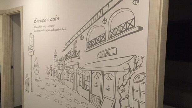 A wall mural of a street scene with a cafe named 'Europe's cafe' serving coffee and sandwiches. - Incheon Airport Happy Place Guesthouse (Incheon)