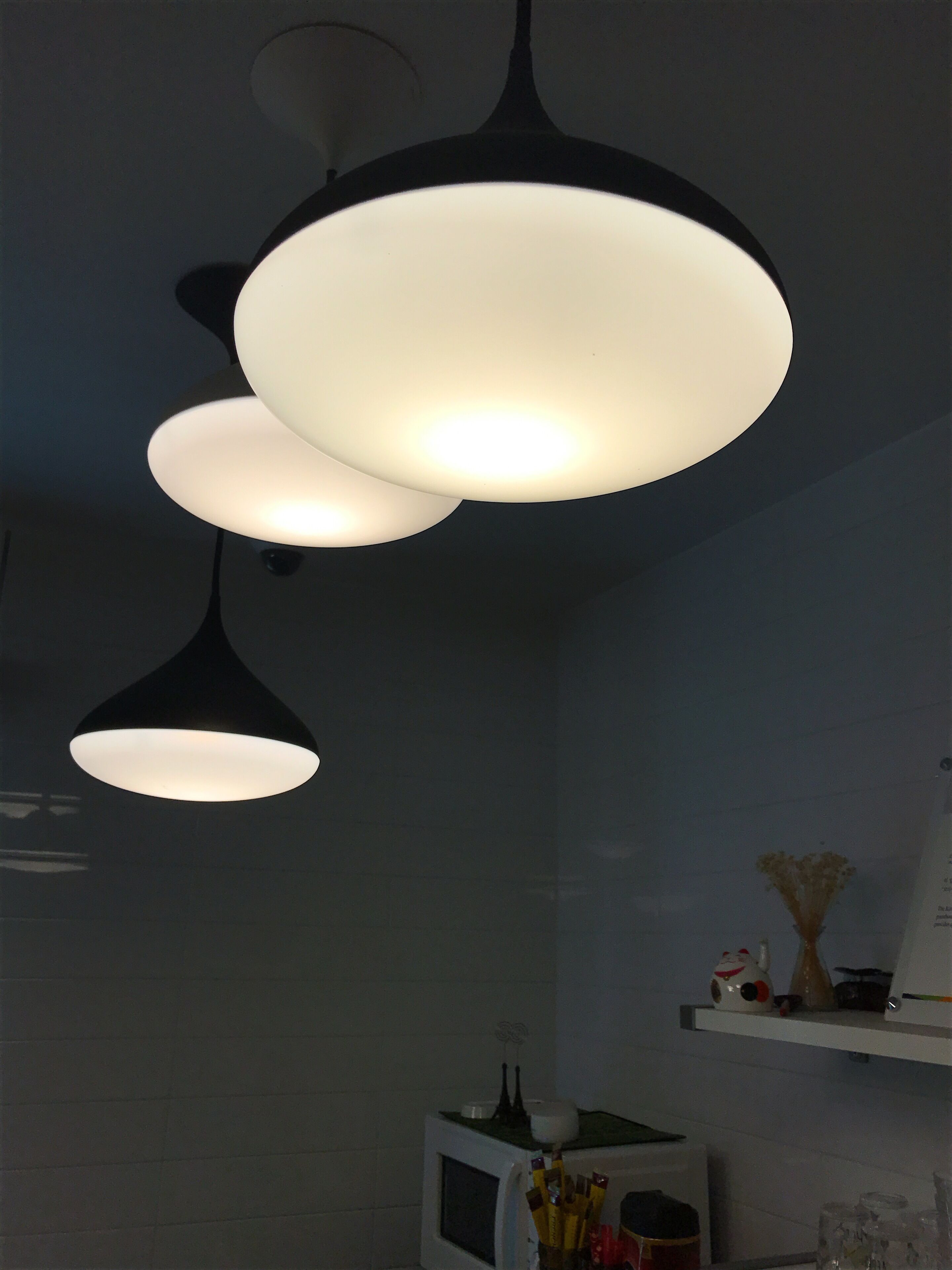 Een keuken met hanglampen, een magnetron en een plank met keukengerei.