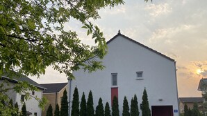 A white building with a red door, surrounded by tall, narrow trees. - Incheon Airport Happy Place Guesthouse (Incheon)