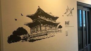 A wall with a black silhouette of a traditional Korean building, a small tree, and a bird. - Incheon Airport Happy Place Guesthouse (Incheon)