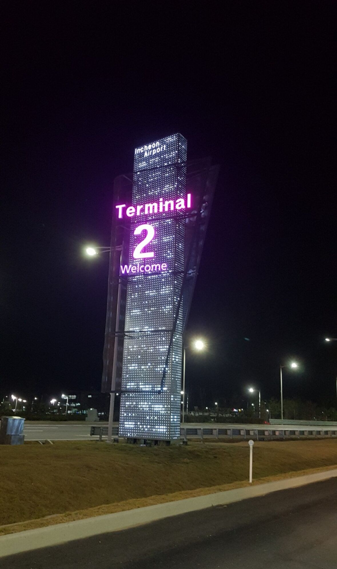 Een hoog, verlicht bord waarop duidelijk 'Terminal 2 Welkom' staat.