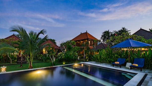 A swimming pool with lounge chairs and umbrellas, surrounded by lush greenery and traditional architecture. - The Cozy Villas Lembongan by ABM (Lembongan Island)