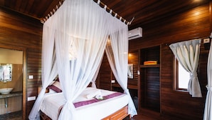A wooden cabin-style bedroom with a four-poster canopy bed, a wooden floor, and a built-in shelf with a mirror and decorative items. - The Cozy Villas Lembongan by ABM (Lembongan Island)