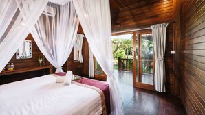 A bedroom with a canopy bed, wooden walls, a balcony with glass doors, and a view of greenery outside. - The Cozy Villas Lembongan by ABM (Lembongan Island)