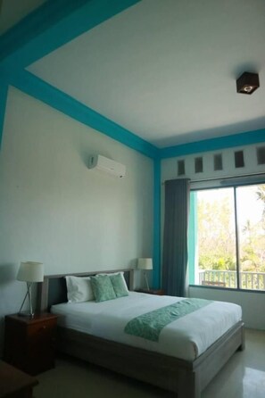 A bedroom with a large bed, two bedside tables, a window with curtains, and a ceiling light fixture. - Villa Rembulan (Gili Trawangan)